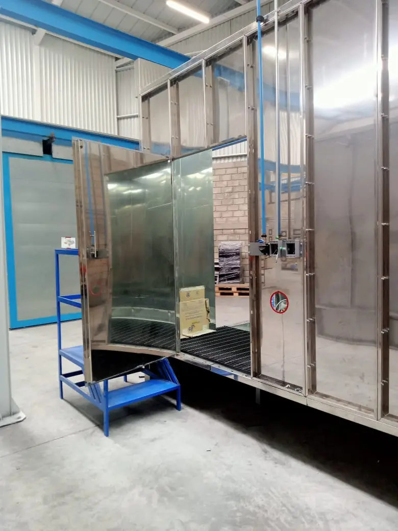 Cabina con puerta abierta en una línea de pintura